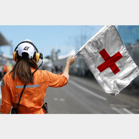 Commissaire de course levant un drapeau blanc à croix rouge pour signaler une intervention médicale