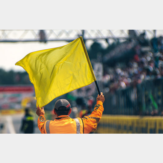 Drapeau jaune levé par un commissaire – signal de danger sur piste en sport auto ou karting