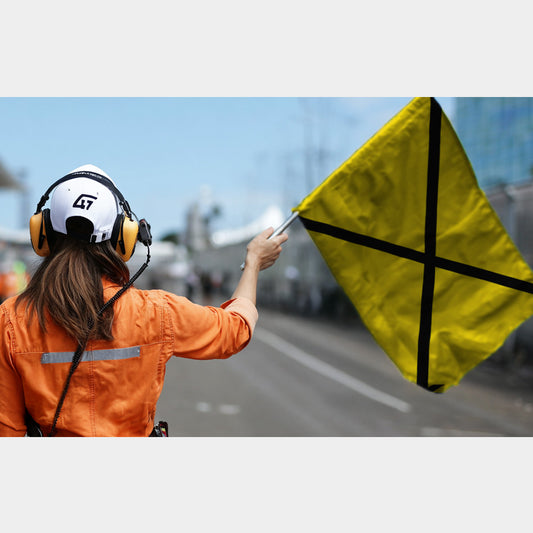 Drapeau de course jaune à croix noire en X, signalant une panne mécanique sur circuit