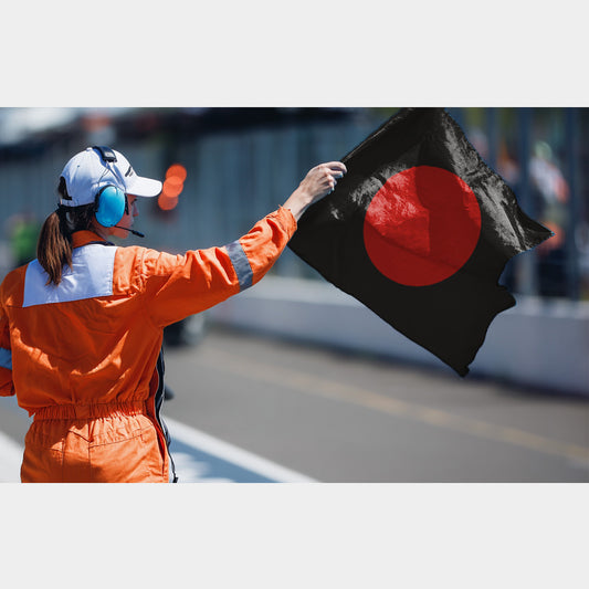 Drapeau de course noir avec un disque rouge tenu par un commissaire sur circuit